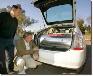 The researchers next to the hydrogen tank in the hybrid car