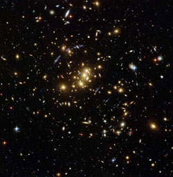 This galaxy cluster allows astronomers to trace the distribution of dark matter in the universe, the blue arcs around the center of the image are actually smears of very distant galaxies that are not part of the cluster. The distant galaxies appear distorted because their stars have been flattened and enlarged by the cluster's strong gravity.