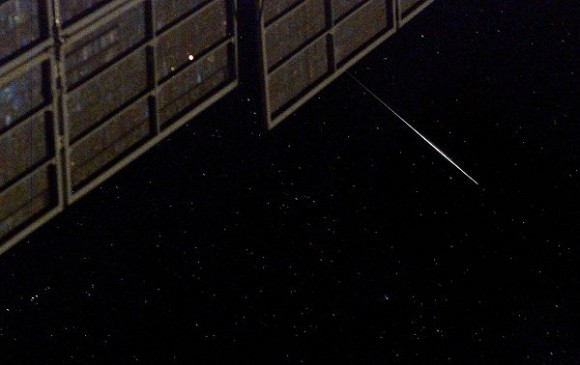 הבזק של לוויין אירידיום המפנה את קולטי השמש לעבר המצלמה ולכן נראה כמו רצועת אור, כפי שצולם מתחנת החלל הבינלאומית. צילום ארכיון דון פטיט, נאס''א