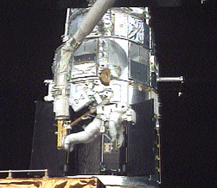 Astronaut Mission Specialist Drew Feustel rides the shuttle Atlantis robotic arm while working on the Hubble Space Telescope during the third spacewalk, May 16, 2009