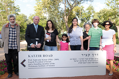أفراد عائلة كاتسير مع البروفيسور دانييل زيفمان بالقرب من اللافتة الجديدة لديرخ كاتسير