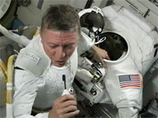 האסטרונאוט מייק פוסום מבצע חזרה בעטיית חליפת חלל במינעל החלל קווסט. צילום: NASA TV