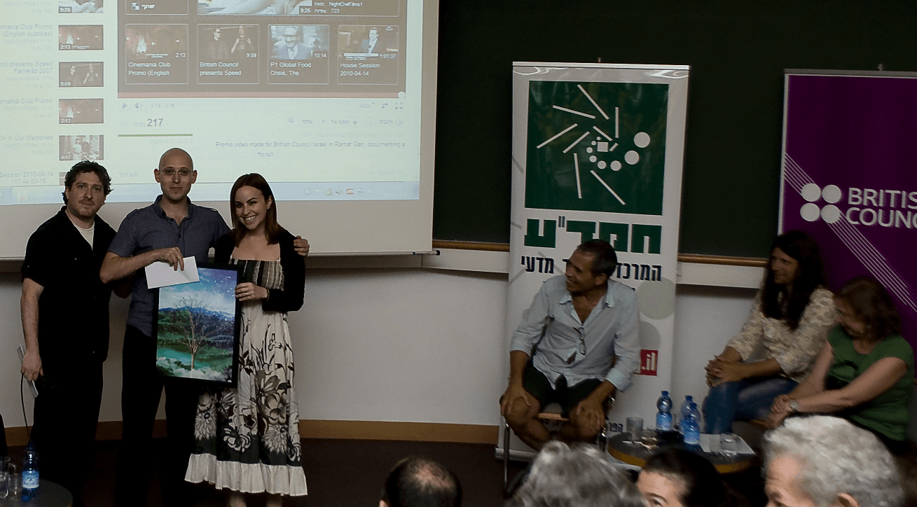 רועי צזנה (באמצע) מקבל את הפרס בתחרות סרטוני מדע ויראליים מידיהם של ג'וליה טוביאס ואורי אביב