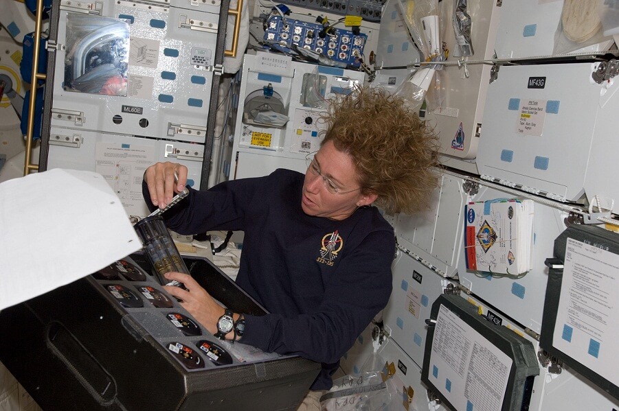 האסטרונאוטית האמריקאית סאנדי מאגנוס, מצוות מעבורת החלל אטלנטיס, בעת השלמת ביצוע ניוסי טיהור המים של שטראוס מים בחלל ואבטחתו בתא האחסון לקראת נחיתה. (צילום: נאס"א)