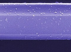 תמונת מיקרוסקופ אלקטרוני סורק של מקטע חיישן גז המורכב מננו-חוט מוליך-למחצה של גאליום ניטריד. ננו-החוט, שעוביו פחות מ- 500 ננומטרים, מצופה בננו-צברים של דו-תחמוצת הטיטאניום, אשר משנים את הזרם העובר בננו-החוט בנוכחות של תרכובת אורגנית נדיפה ובחשיפה לקרינה על-סגולה. באדיבות: NIST