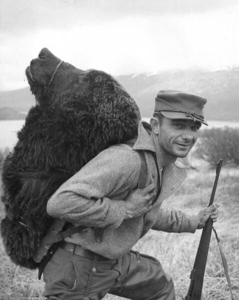 A happy hunter carries the head of a Kodiak bear. Photo: US Forest and Wildlife Service. From Wikipedia