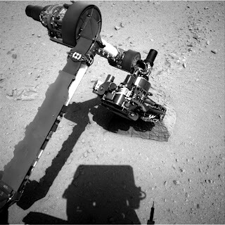 הזרוע הרובוטית של קיוריוסיטי בוחנת סלע ששמו ג'ייק, שנראה מיוחד לסביבה בה הוא התגלה.
