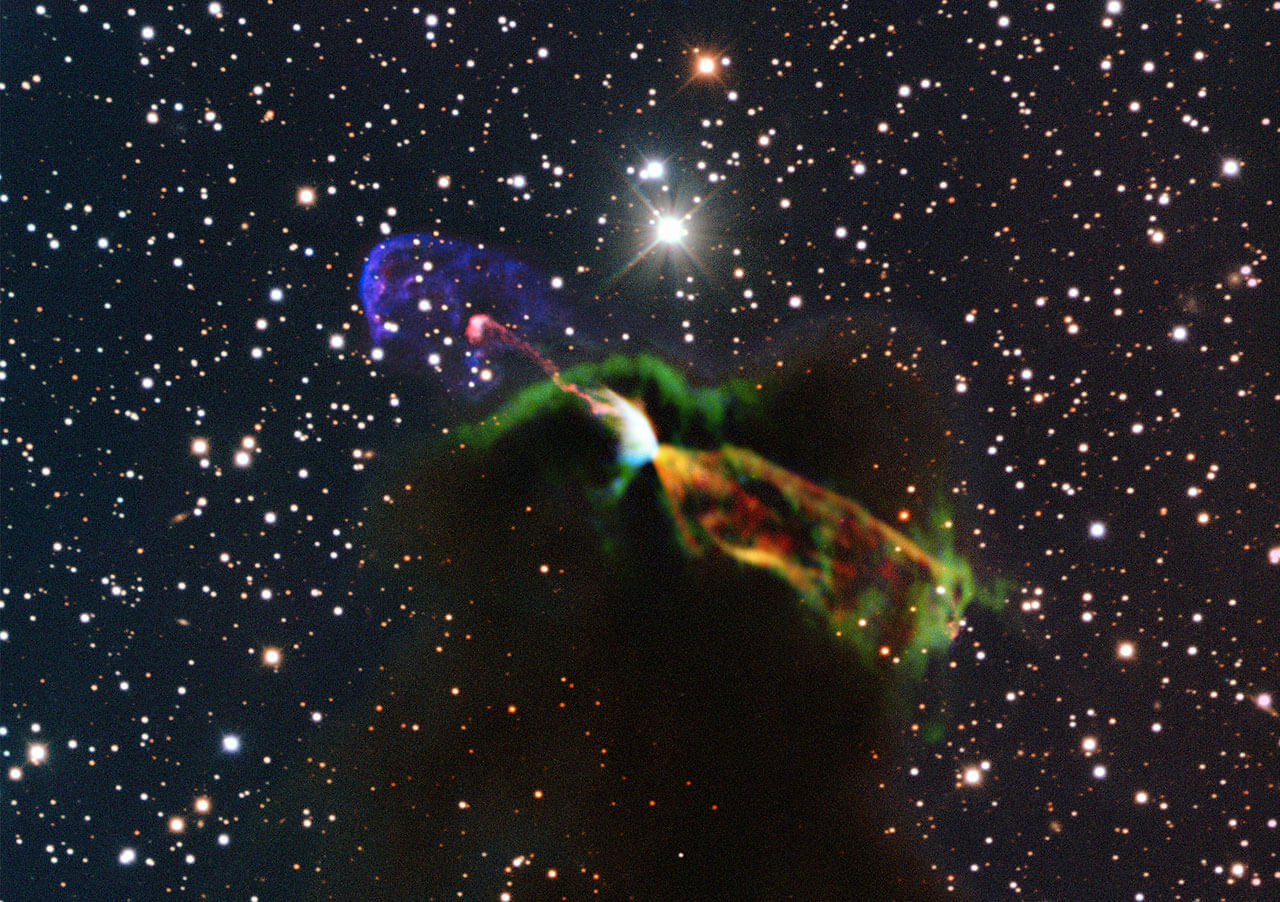 An unprecedented photograph of the object Herbig-Haro 46/47 combining radio observations from the Alma Observatory with much shorter wavelength photographs of visible light from ESO's New Technology Telescope. Alma observations (orange and green, lower right) of the newborn star reveal a large energetic jet moving away from us, hidden by the dust and gas in the nebula where the star was born. On the left side (in pink and purple) we see the visible part of the jet, partially flying towards us. Photo: European Southern Observatory (ESO)