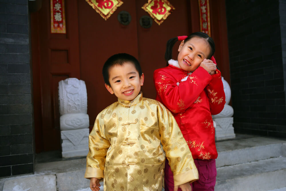 ילדים סינים בתלבושת מסורתית, ליד בית מקושט בקישוטים סיניים. צילום: shutterstock