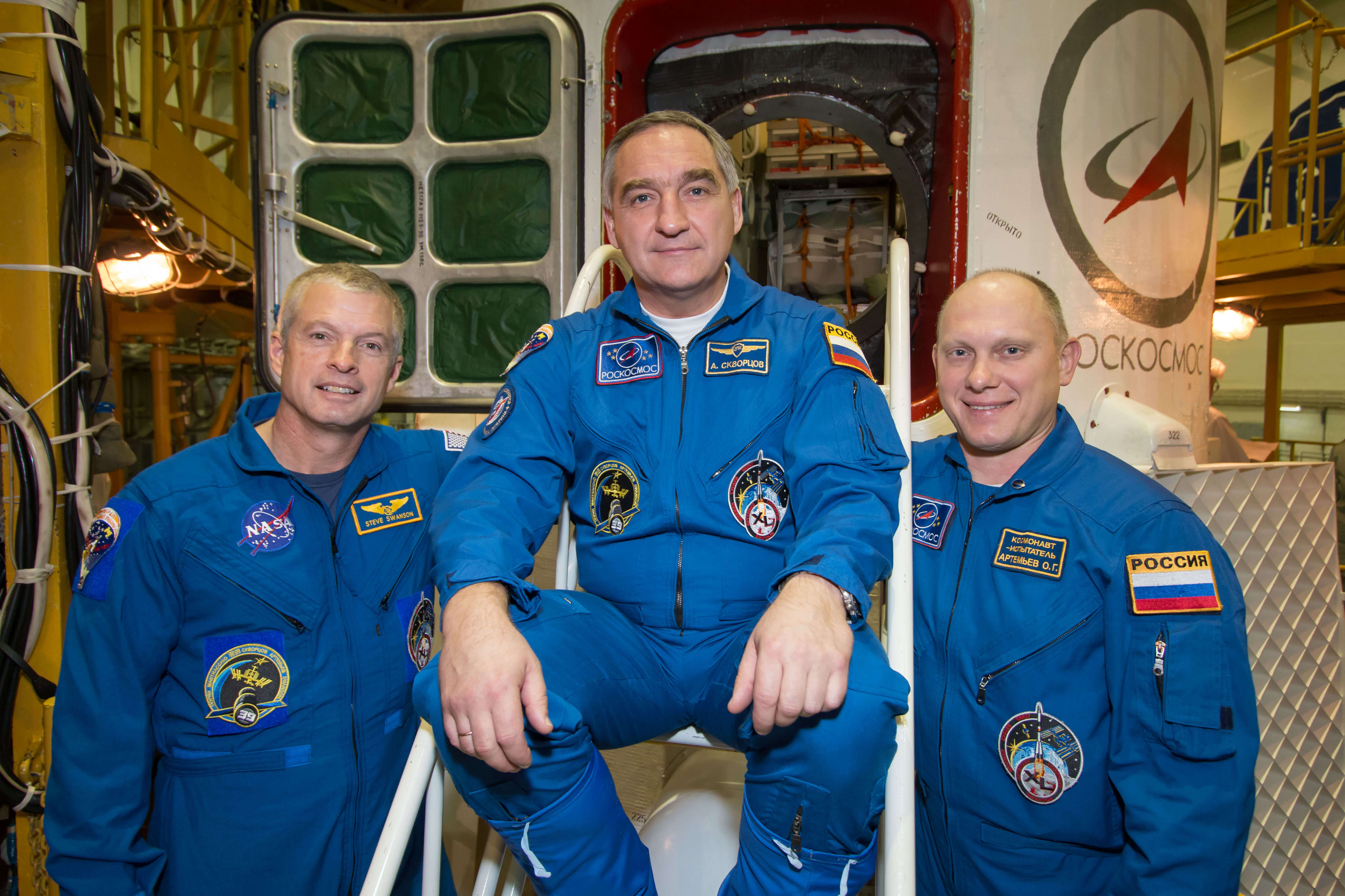 במרכז האינטגרציה בקוסמודרום בייקונור בקרחסטן מתאמנים אסטרונאוט נאס"א סטיב סוונסון (משמאל), ועמיתיו הרוסים אלכסנדר דקבורטסטוב (במרכז) ואולג ארטמייב ליד החללית סויוז TMA-12M ב-21 במארס 2014 לקראת שיגורם ב-26 לחודש. צילום: נאס"א/ויקטור זלנטסוב