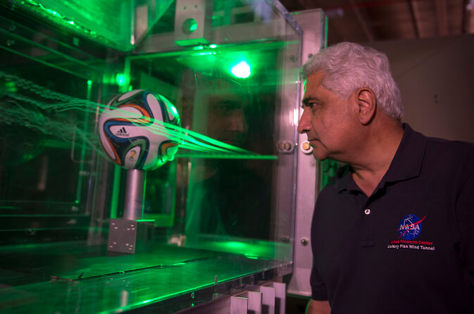 ד"ר ראבי מהטה משתמש בעשן ולייזרים כדי לחקור את תבניות הזרימה סביב כדור בראזוקה של אדידס לקראת המונדיאל - גביע העולם FIFA 2014. צילום: מרכז המחקר איימס של נאס"א.