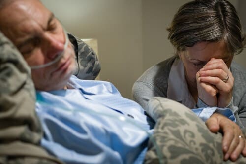 A woman sits by the bed of a comatose man. Illustration: shutterstock