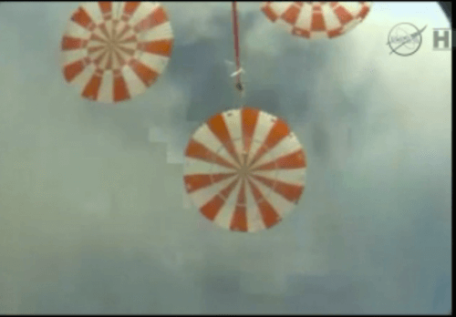 החללית אוריון מצלמת את המצנחים שמעליה, כדקה לפני הנחיתה באוקיאנוס השקט. מתוך הטלוויזיה של נאס"א