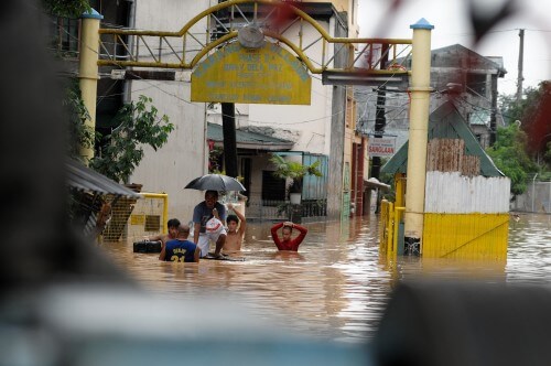 Residents of the village of Karangalan in the Philippines swim in the main street of the village after it was flooded by the rains of Typhoon Ondoy. Hundreds of people were killed in that event. 2009. Photo: Timothy Medrano / Shutterstock.com