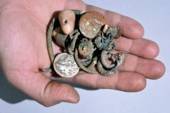 מטבעות של אלכסנדר מוקדון, שלוש טבעות, ארבעה צמידים, 2 עגילים מעוטרים, 3 עגילים נוספים (ככל הנראה עשוים כסף), ומשקולת אבן קטנה. צילום: קלרה עמית, באדיבות רשות העתיקות