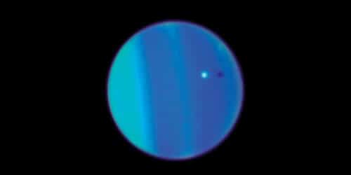 The moon Ariel (in white) and its shadow (the black dot) against the background of the planet Uranus. Photo: Hubble Space Telescope