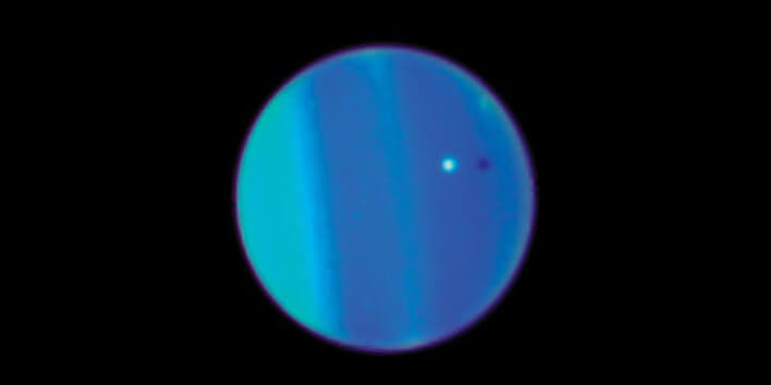 הירח אריאל (בלבן) וצילו (הנקודה השחורה) על רקע כוכב הלכת אורנוס. צילום: טלסקופ החלל האבל