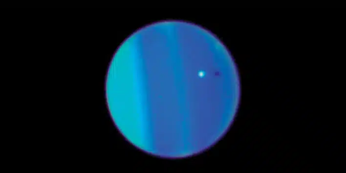 הירח אריאל (בלבן) וצילו (הנקודה השחורה) על רקע כוכב הלכת אורנוס. צילום: טלסקופ החלל האבל