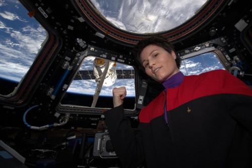 מהנדסת הטיסה סמנתה Cristoforetti מסוכנות החלל האירופית במדים של סדרת מסע בין כוכבים על רקע  החללית דראגון של SpaceX הגיעה לתחנת החלל הבינלאומית ב -17 באפריל, 2015 מלאה באספקה. צילום: נאס"א.