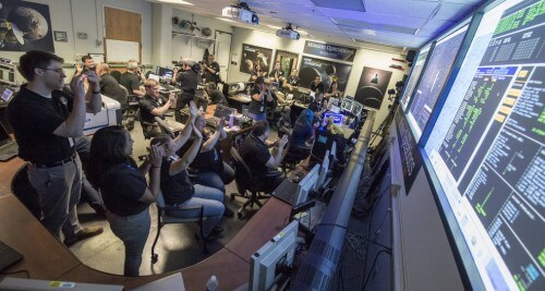 אנשי צוות ניו הוריזונס חוגגגים לאחר קבלת האישור שהיא השלימה בהצלחה את המעבר לידפלוטו במרכז התפעול של המשימה במעבדה לפיזיקה יישומית באוניברסיטת ג'ונס הופקינס במרילנד. צילום: NASA/Bill Ingalls