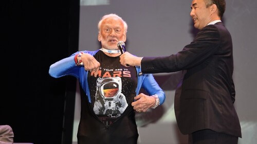 رائد الفضاء باز ألدرين يقدم قميصًا مكتوبًا عليه دعوة للذهاب إلى المريخ وصورة شخصية التقطها في الفضاء عام 1966. الصورة: إسرائيل بن إيلي، الرئيس التنفيذي