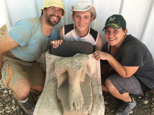 תמונה של הפסל יחד עם החופרים שמצאו אותו (כתובית: המתנדבים בחפירה שמצאו את הפסל המצרי, מימין - אלנה סוואט מדרום אפריקה, בריאן קובאץ’ מארצות הברית ו-ואלנטין סמה-רוחו מספרד. שלושת החופרים הם מתנדבים חוזרים, כלומר שזוהי לא השנה הראשונה שלהם בחצור). צילום: שלומית בכר