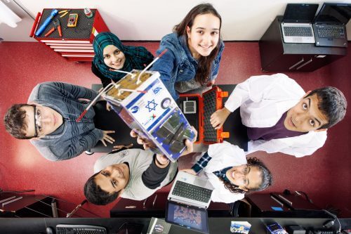 Students holding the Dukhipat 2 satellite while assembling it. PR photo - Herzliya Science Center