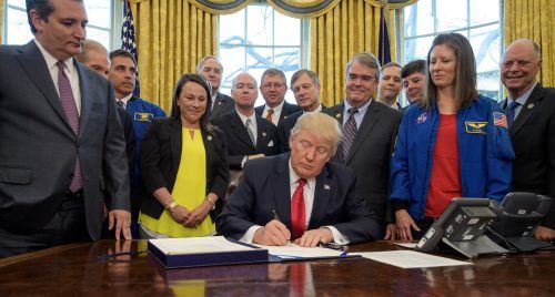 Trump signs the law in the Oval Office. Source: NASA/Bill Ingalls.