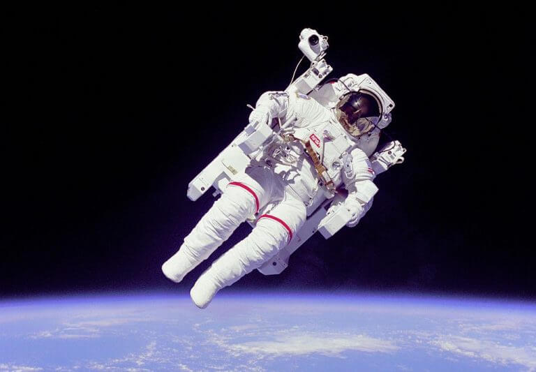 אסטרונאוט אמריקאי בחליפת חלל לבנה להליכות חלל, שהוספה לה יחידת הנעה עצמאית (Manned Maneuvering Unit), שאפשרה לאסטרונאוט להתרחק ממעבורת החלל. השימוש ביחידת ההנעה העצמאית היה מוגבל מאד, ונעשה בה שימוש רק שלושה פעמים ב-1984. צילום: NASA.