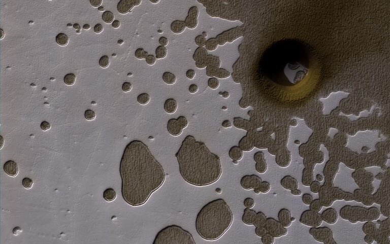 חורי "הגבינה השוויצרית" בקוטב הדרומי של מאדים. החומר הלבן בתמונה הוא קרח יבש - העשוי מפחמן דו-חמצני. השקעים בשכבת הקרח היבש מגיעים לעומק של עד 10 מטר בלבד. הם נוצרים בעונת הקיץ המאדימית, אז קרני השמש פוגעות בזווית נמוכה באזור הקטבים, ומגיעות בעיקר לקירות התלולים של השקעים - מה שמעודד התפתחות לרוחב ולא לעומק. לצילום, ברזולוציה המלאה שלו, יש רזולוציה של 50 סנטימטר לפיקסל. צולם ב-25 במרץ 2017 על ידי הגשושית MRO של נאס"א, הנמצאת במסלול סביב מאדים. מקור: NASA/JPL-Caltech/Univ. of Arizona.
