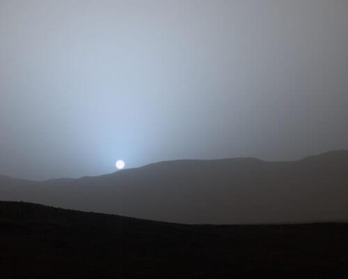 שקיעת השמש, כפי שתועדה על ידי קיוריוסיטי ב-15 באפריל 2015. בניגוד לשקיעות הכתומות וצהובות בכדור הארץ, במאדים האבק הרב באטמוספירה חדיר יותר לצבע כחול, ולכן בשקיעות, כאשר האור נדרש לעבר דרך חלק גדול יותר מהאטמוספירה עקב זווית הפגיעה, אור השמש מקבל גוון ازرق. المصدر: NASA/JPL-Caltech/MSSS/Texas A&M Univ.