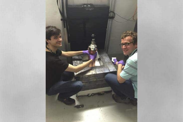 משמאל ביורן שולץ מאוניברסיטת שיקאגו וגרייסון ריץ' מאוניברסיטת צפון קרוליינה בצ'אפל היל מחזיקים את בקבוק יודיד הצזיום שבו קלטו התנגשוית חלקיקי ניוטרינו. צילום: ORNL