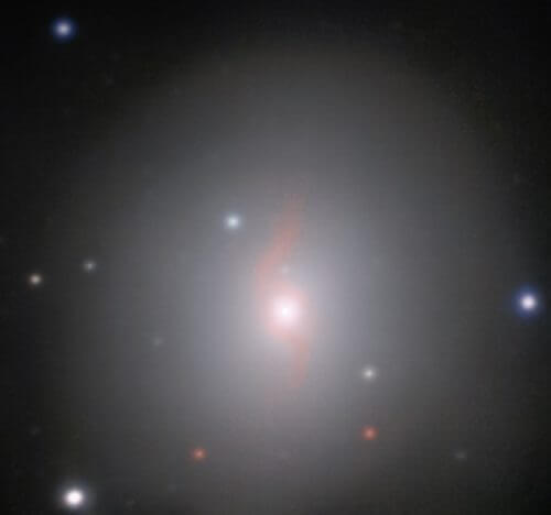 גלקסיית NGC 4993 המרוחקת 130 מיליון שנות אור מכדור הארץ. ניתן לזהות את ה"חתימה האופטית" של הקילונובה משמאל למרכז הגלקסיה. התמונה צולמה באמצעות מיכשור MUSE (ספקטרוסקופיה מרובת עצמים) ב"טלסקופ הגדול מאוד" של איס"ו הממוקם במצפה הכוכבים פאראנאל בצ'ילה. מקור: ESO/J.D. Lyman, A.J. Levan, N.R. Tanvir.