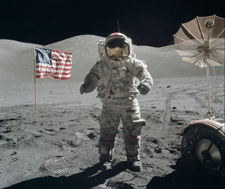 האסטרונאוט ג'ין סרנן על קרקע הירח, ליד דגל אמריקאי כלצידו מבצבץ רכב הנדידה הירחי, דצמבר 2017. טקס ההכרזה על החזרה האמריקאית לירח התבצע אתמול, 11 בדצמבר, ביום בו צוינו 45 שנה לנחיתת אפולו 17 על קרקע הירח , המשימה המאוישת האחרונה בתוכנית אפולו. מקור: NASA / Harrison H. Schmitt.