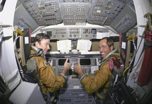 يونغ (يسار) ومساعد الطيار روبرت كريبن، أثناء الاستعدادات لرحلة المكوك الأولى، 1980. المصدر: ناسا.