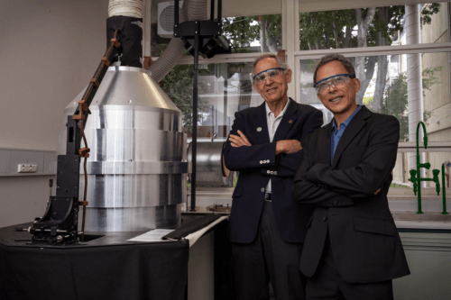 البروفيسور جيفري جوردون (يسار) والبروفيسور هوي تونج تشوا بجوار نظام إنتاج المواد على شكل بصل نانو، ثمرة تطورهم