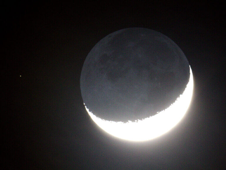 The dark part of the moon is visible next to the bright scythe. Source: Radoslaw Ziomber, Wikimedia