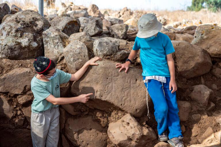 Children from Hispin who volunteer in the excavation point to the figures blackened on the stone. Photo: Yaniv Berman, Antiquities Authority