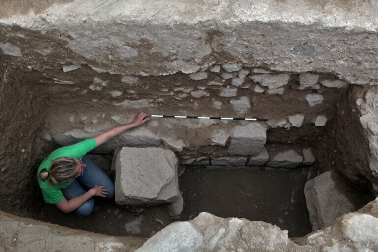 Dr. Citrin-Salberman places a scale on a remnant of a Roman monumental structure that is under the earliest mosque, and above it appears a foundation belonging to the ancient mosque. Photo by NETP, David Salberman