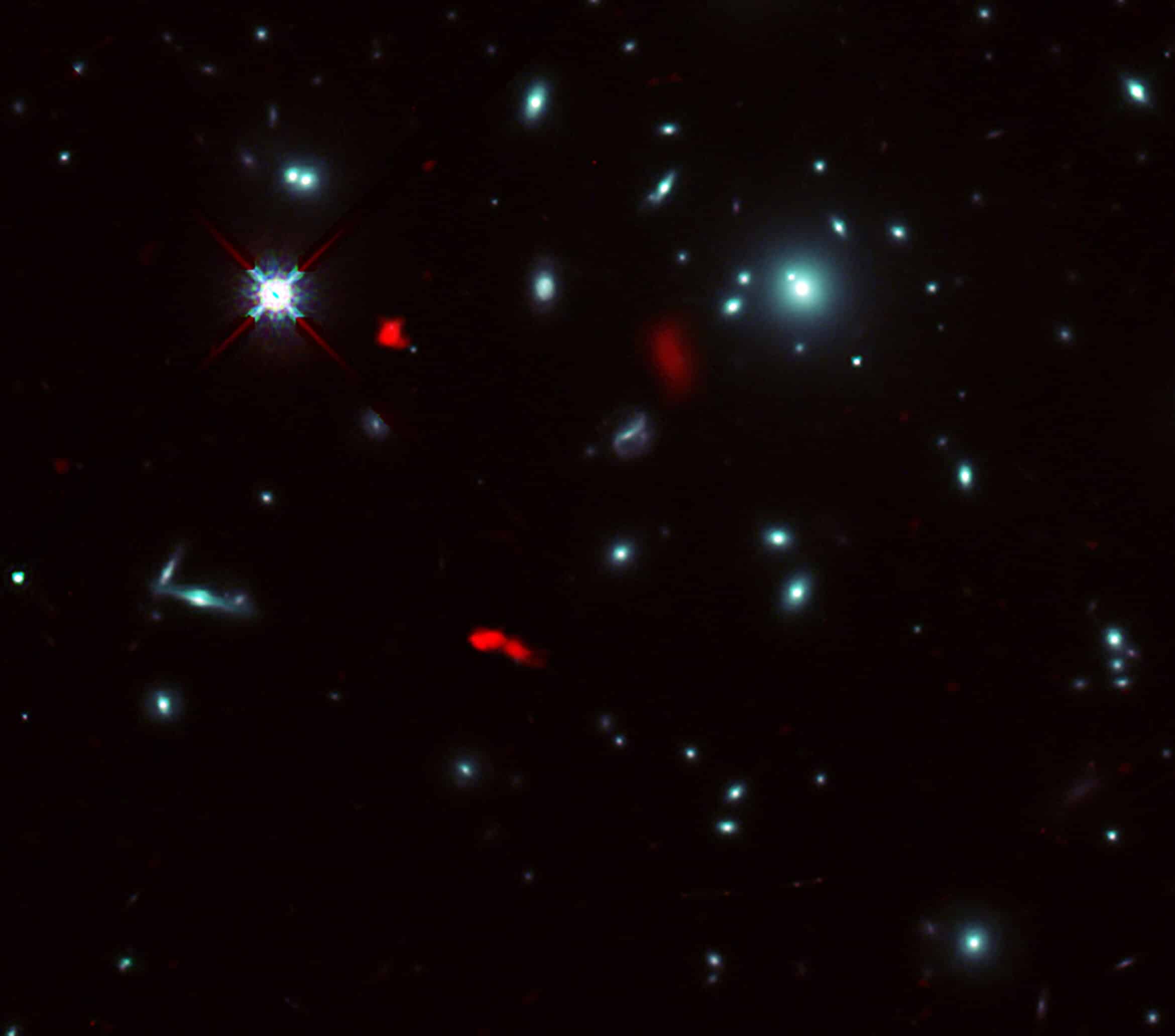 The galaxy cluster RXCJ0600-2007 imaged by the NASA/ESA Hubble Space Telescope, combined with gravitational lensing images of the distant galaxy RXCJ0600-z6, 12.4 billion light-years away, observed by ALMA (shown in red). Due to the gravitational lensing effect of the galaxy cluster, the image of RXCJ0600-z6 has been intensified and magnified, appearing to be divided into three or more parts.Credit: ALMA (ESO/NAOJ/NRAO), Fujimoto et al., NASA/ESA Hubble Space Telescope