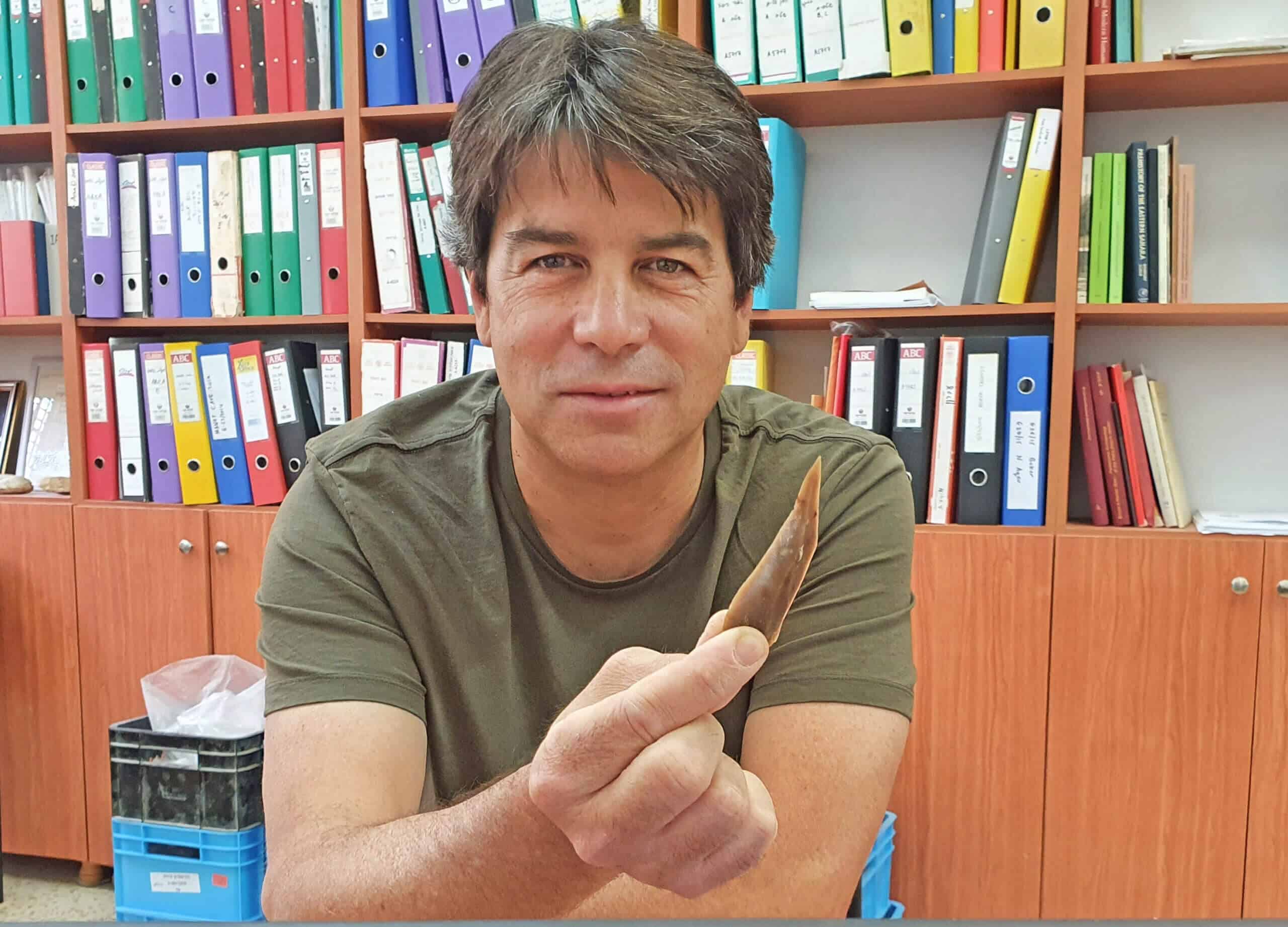 הפרה-הסטוריון, פרופ' עמרי ברזילי מחזיק בידו אבן צור מהחפירות באתר בוקר תחתית. צילום: רשות העתיקות