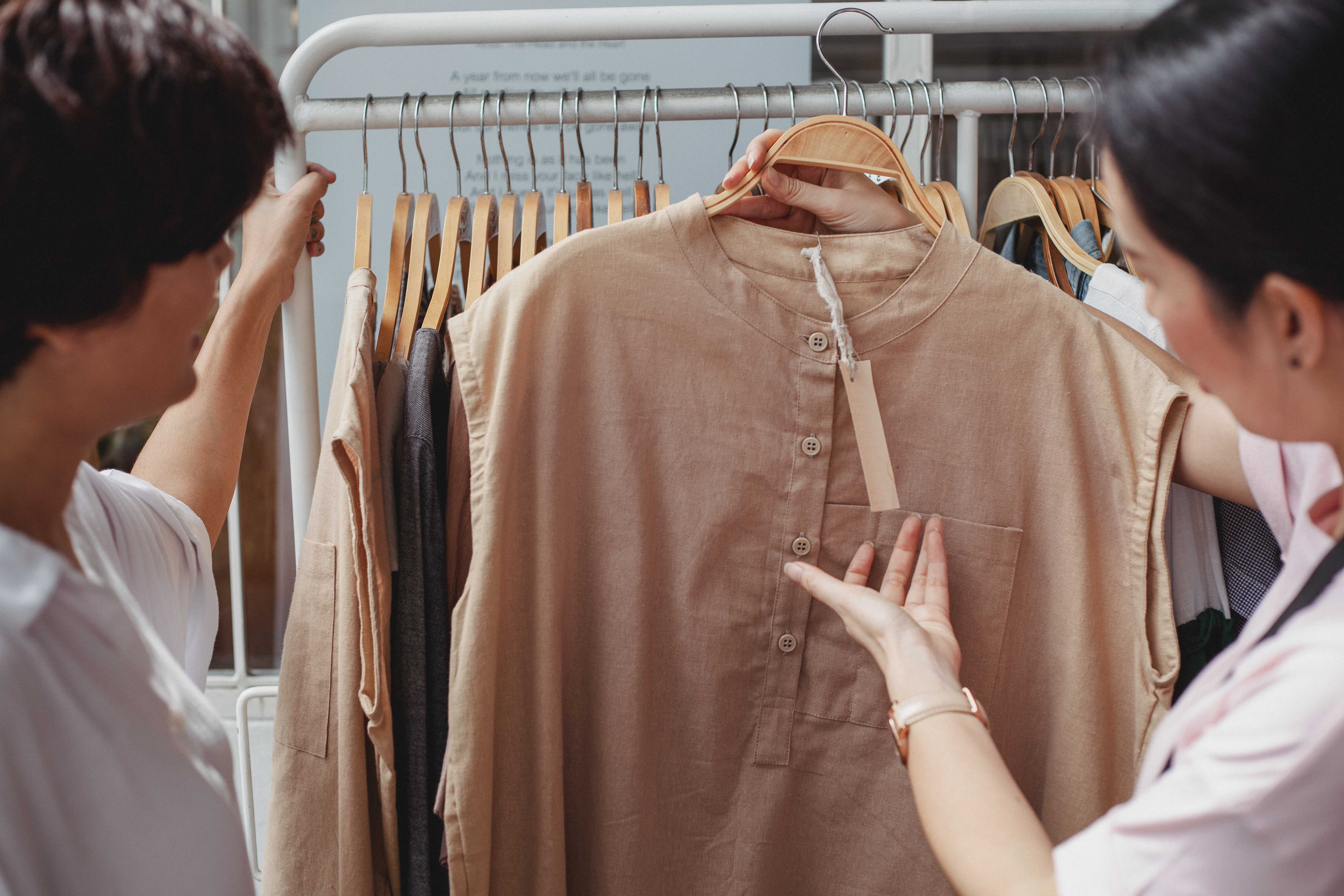 Crop asian shoppers interacting while choosing clothes in shop