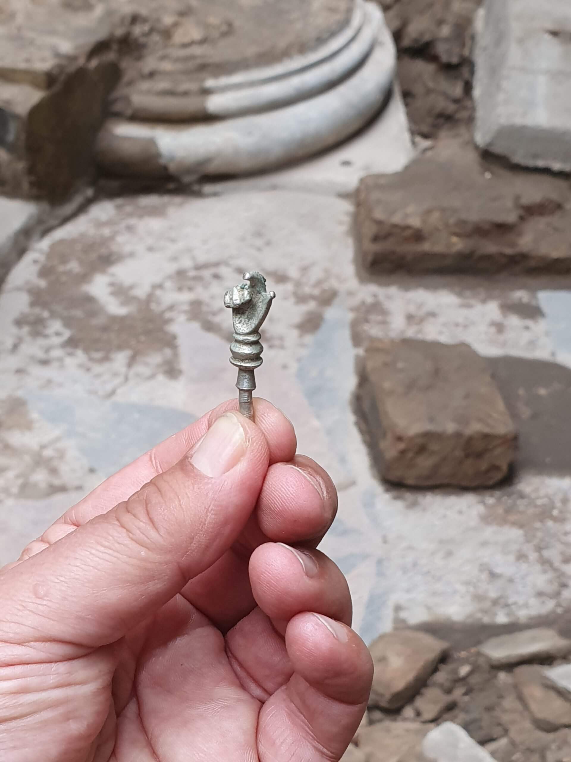 The silver hand that was revealed against the background of the synagogue stage where it was discovered. Photo by John Seligman, Israel Antiquities Authority