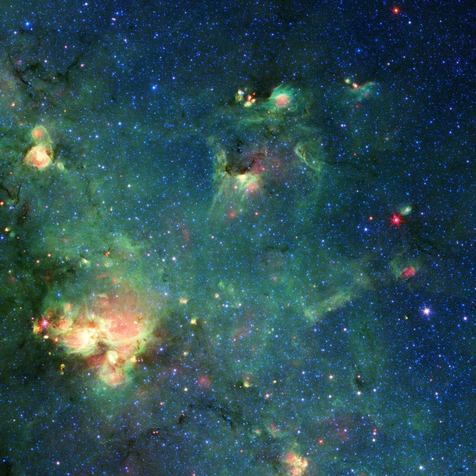טלסקופ החלל ספיצר של נאס"א צילם את ענן הגז והאבק הזה. הצבעים מייצגים אורכי גל שונים של אור אינפרה אדום ויכולים לחשוף תכונות כמו מקומות שבהם קרינה מכוכבים חיממה את החומר שמסביב. כל דמיון לגודזילה הוא אך ורק מדומיין. קרדיט: NASA/JPL-Caltech