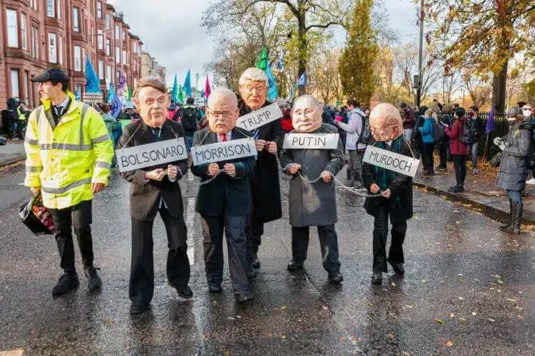 מפגינים חובשים מסיכות של מנהיגים האשמים במשבר האקלים כמי שנאסרו בשל כך בגלזגו, סקוטלנד במהלך ועידת COP26. צילום: shutterstock