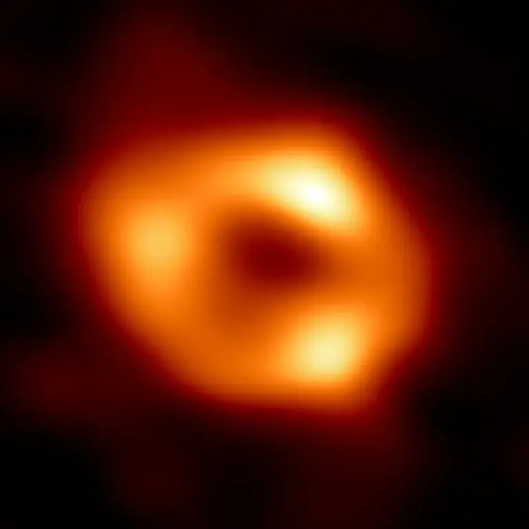 This is the first photograph of Sagittarius A* the supermassive black hole at the center of our galaxy. This is the first direct visual evidence of the presence of this black hole. Until now, it has been recognized for its influence on the stars close to it. The black hole was imaged using the Event Horizon Telescope (EHT), an array that joined together eight existing radio observatories around Earth to create one virtual "Earth-sized" telescope. The telescope is named after the event horizon, a nickname for the boundary of the black hole beyond which no light can escape. Credit: EHT Partnership
