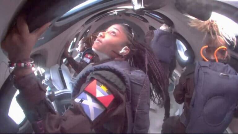 אנסטסיה מאיירס בעת השהות בחוסר משקל בחללית יוניטי של וירג'ין גלקטיק בטיסה המסחרית 02. ברקע נראית אמה קישה שחף ועל זרועה דגל ישראל. צילום: וירג'ין גלקטיק