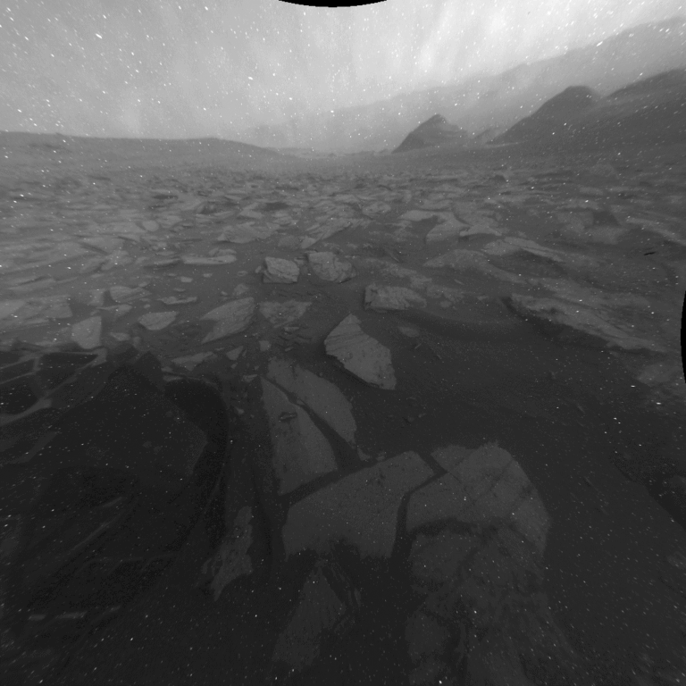Curiosity's rear Hazcam recorded the shadow of the rover's rear in a 12-hour view toward the Gale Basin floor. Several factors caused several artifacts in the image, including a black spot, the sun's distorted appearance, and rows of white pixels extending from the sun. NASA/JPL-Caltech