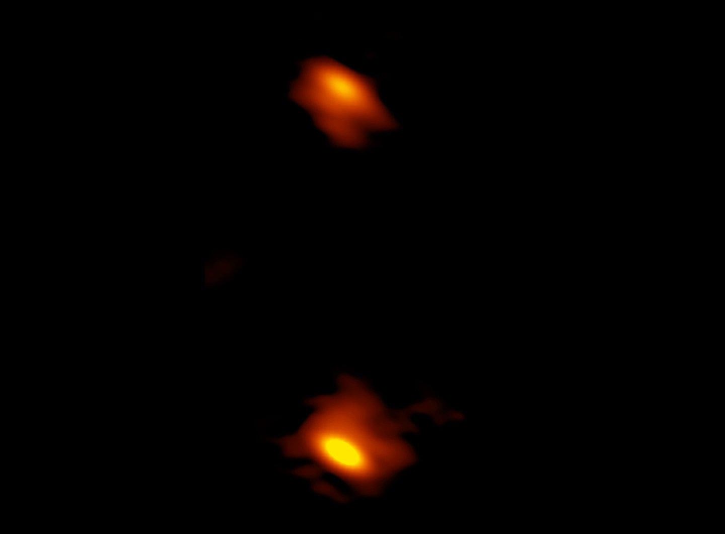 This image taken by VLBA shows two supermassive black holes, which appear as blobs with red streaks. Black holes are at the center of an elliptical galaxy. The colors represent different spectral gradients in radio emission, with red showing the densest regions around the black holes. The black hole on the right must have recently devoured a massive star, causing it to emit two very fast jets. The edges of these jets appear as green spots above and below the black hole. This object, named J0405+3803, is called a CSO because its jets are relatively close (or compact) compared to other black holes with much larger jets. Credit: HL Maness/Grinnell College