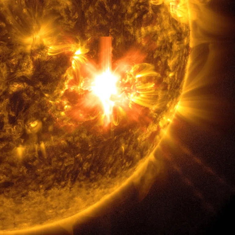 In this photograph from the SDO Solar Observatory, the lower right area of ​​the Sun is shown in gold on a black background. There are several loops coming down from the sun. Towards the middle is a bright white area - the flare of the sun. Solar flares are powerful bursts of energy. Sun flares and solar flares can affect radio communications, power grids, navigation signals, and pose risks to spacecraft and astronauts.